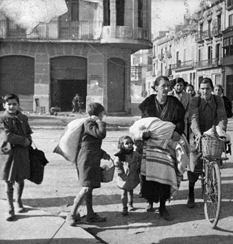 Magdalena Rosell amb els seus fills Jordi, Agustí, Magda i Tomàs Bosch Rosell passant per la Gran Via de Jaume I camí de casa seva, després d'haver fugit durant un dels bombardejos de la Guerra Civil. Febrer 1939