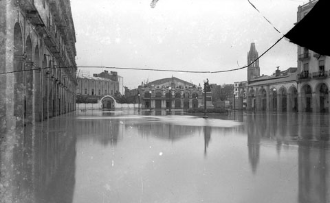 Plaça de Sant Agustí inundada. Només sobresurt el monument als Defensors de Girona. Al fons es veuen els cinemes Coliseu i Albéniz. 1940
