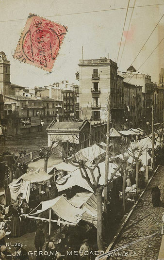 Mercat a l'actual Rambla de la Llibertat. Al centre, les casetes comercials. A l'esquerra sobresurt el campanar de l'església del convent de Santa Clara. 1905-1910