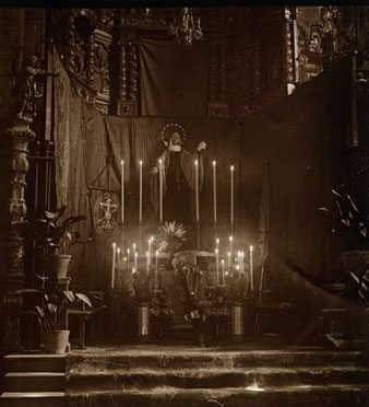 Vista parcial d'un altar ornamentat per la celebració de la Setmana Santa a l'església de Sant Feliu. A la dreta de la imatge s'observen dues dones resant. 29 de març 1923
