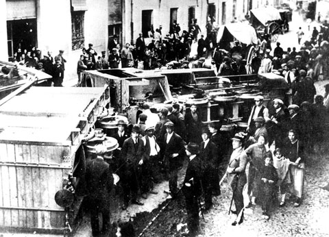 Descarrilament del tren de Palamós a l'altura del nmero 105 del carrer de Pont Major. S'observa un grup de persones mirant el vago descarrilat i nombrosos curiosos al voltant. 1920-1930