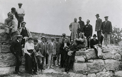 Visita d'un grup d'arqueòlegs a la muralla grega d'Empúries. El quart per la dreta, amb vestit negre i un barret blanc a la mà, Carles Rahola. 1920-1925