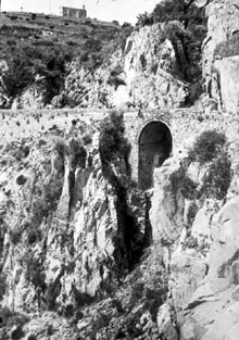 Camí de la punta de Garbí al vessant rocós i al fons la ermita de Sant Elm. 1895-1920