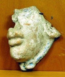 Màscara de terracota. Ex-vot trobat al temple de la part alta del Puig de Sant Andreu. Representa un personatge mitològic (Gorgona, Aquelous), una cara femenina o demoníaca. Segle III aC