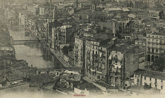 Vista del barri del Mercadal des del campanar de la Catedral. Travessen l'Onyar els ponts de Sant Agustí, de les Peixateries Velles i al fons, el pont de Pedra. En primer terme a la dreta, la plaça de la Independència i al fons, el campanar de l'església de les Bernardes, el de Santa Susanna i les naus i la xemeneia de la fàbrica Gròber. 1919-1925