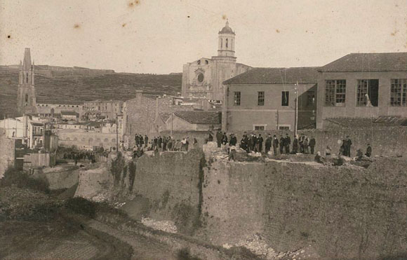 Enderrocament de la muralla del Mercadal a la zona de la Gran Via, a l'altura del baluard de la Santa Creu. En primer terme a la dreta, les naus de la fàbrica Gròber. 1901-1908