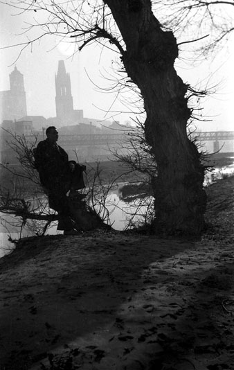 Retrat d'Antoni Varés des de l'altura del Portal de la Barca on s'observa el pont del Ferrocarril, el campanar de Sant Feliu i la Catedral de Girona al fons. 1955-1960