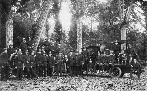 Retrat de grup dels membres de la Companyia Municipal de Bombers amb uniforme i el camió cisterna a la Devesa. 1927