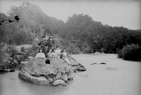 Retrat d'un grup de gent dalt d'una roca, a la vora del riu Ter a l'altura del pas del Congost. 1900-1925