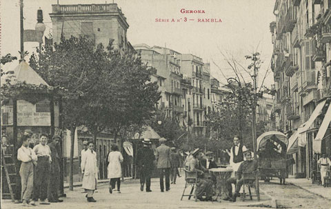 Vista de la la part alta de la Rambla de la Llibertat amb uns homes asseguts a la terrassa del Cafè Exprés. A l'esquerra s'observa el quiosc. A la dreta hi circula una carruatge. 1920