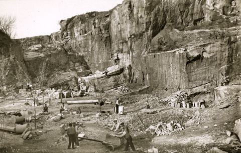 Picapedrers treballant a la pedrera Pruneda. En primer terme, un carro de llança per al transport de blocs de pedra. 1930