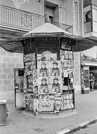 Quiosc de periòdics a davant de la Clínica l'Esperança, actual 'Casa Cacao' de Jordi Roca, a la plaça Catalunya. 1968
