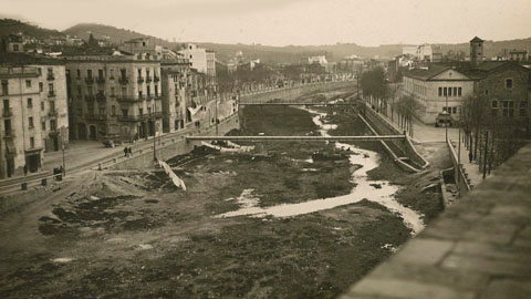 L'Areny del riu Onyar amb el pont del Pes de la Palla i el pont del Carme. A la dreta, davant el convent de Sant Francesc de Paula, s'hi observa el quiosc de begudes. 1927