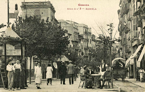Vista de la la part alta de la Rambla de la Llibertat amb uns homes asseguts a la terrassa del Cafè Exprés. A l'esquerra s'observa el quiosc. 1910