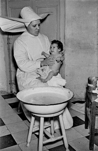 Una monja rentant un nadó a l'Hospici. 1955
