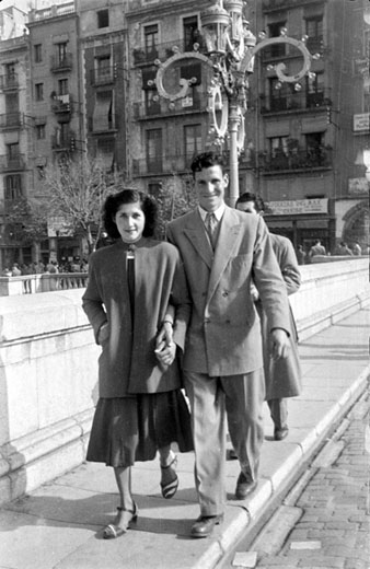 Retrat d'una parella al pont de Pedra amb els fanals engalanats. 1949