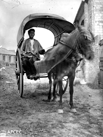 Retrat d'un home en una tartana al costat d'un edifici. 1900-1920