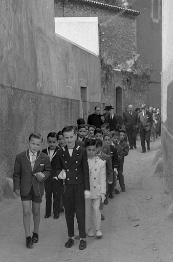 Primera Comunió d'alumnes de les Escoles d'Ensenyament Primari de Foment de Cultura a Girona. Recorregut dels alumnes i els assistents des de l'església dels Dolors fins al Cinema Modern, en el seu pas pel carrer del Portal Nou. 1953