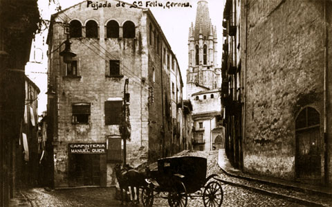 L'esgl&eacute;sia i pujada de Sant Feliu vistes des de la part baixa. A l'esquerra, l'inici del carrer Calderers i la fusteria de Manuel Quer. 1911