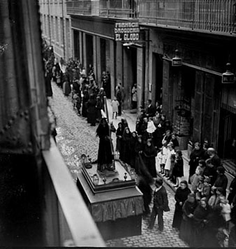 Celebració del Divendres Sant. Vista de la processó al seu pas pel carrer Nou des del balcó de la casa Batlle. Al fons, la farmàcia i la drogueria El Globo