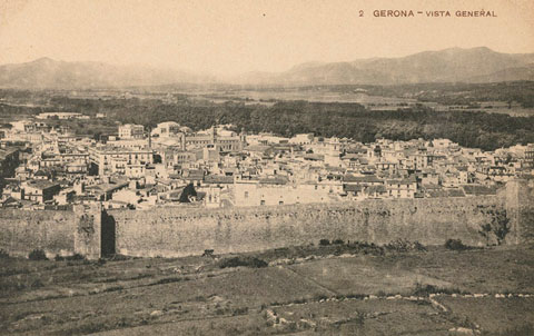 Vista del barri del Mercadal des de la muntanya de les Pedreres. En primer terme el tram de la muralla compr&eacute;s entre la torre del Portal Nou i la torre dels Socors. Al fons, d'esquerra a dreta, les torres de l'esgl&eacute;sia del Sagrat Cor, les naus de la f&agrave;brica Gr�ber i el campanar de l'esgl&eacute;sia de Santa Susanna i de les Bernardes. Al centre, la pla&ccedil;a de Braus de Girona. 1910-1918