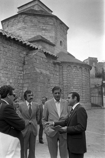 Visita del Director General de Patrimonio Artístico y Cultural, Miguel Alonso Baquer, a la ciutat de Girona. El Director General conversa amb les autoritats a l'exterior de l'església de Sant Nicolau. S'identifica el delegat provincial de Belles Arts, Pere Freixas. 12 d'agost 1975