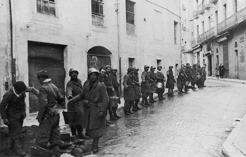 Soldats de les tropes franquistes al carrer de Santa Clara disposats en cadena per tal de fer arribar laigua a la Casa Boué, el 4 de febrer de 1939